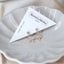 Gold flower-shaped stud earrings with sparkling crystal petals displayed on a BenittaMoko Jewelry card inside a soft beige ceramic dish.
