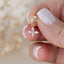 Close-up of a hand holding a gold flower-shaped stud earring with sparkling marquise-cut crystals, ideal for dainty and feminine jewelry lovers.