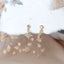 Gold North Star and Crescent Moon mismatched stud earrings with clear crystal accents, displayed on a soft fabric background with dried flowers for an ethereal, celestial look.