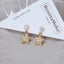 Gold star charm earrings with crystal studs and pavé rhinestones, perfect for statement sparkle, party outfits, or glam holiday jewelry.