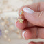 Close-up of a hand holding a gold star charm stud earring with a sparkling rhinestone top and pavé crystal star, showcasing delicate and elegant design.