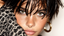 Video.Close-up portrait of a woman with wet hair, wearing a gold septum ring, large gold hoop earring, and leopard print clothing, showcasing a bold and stylish look.