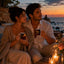 Couple holding Midnight Love Rhythms romantic mugs by the sea at sunset