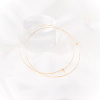 Gold hoop earrings with a diameter of 3 inches resting on white silk fabric. The earrings are designed in a classic circular shape and feature a shiny, reflective surface. They are suitable for various occasions and add a stylish accessory to any outfit