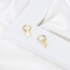 Gold plated huggie earrings displayed on a white frame with white silk. The unique, wavy design adds elegance and sophistication. It can be worn alone or combined with other hoop earrings