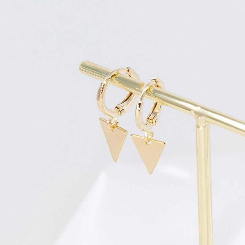 Gold-plated hoop earrings with triangle charm hanging on a stand in a golden color. The hoop earrings feature a sleek, minimalist design with a delicate triangle charm that adds a touch of sophistication and style. The gold plating gives the earrings a luxurious and elegant look, and the stand provides a modern and stylish display for showcasing the earrings."